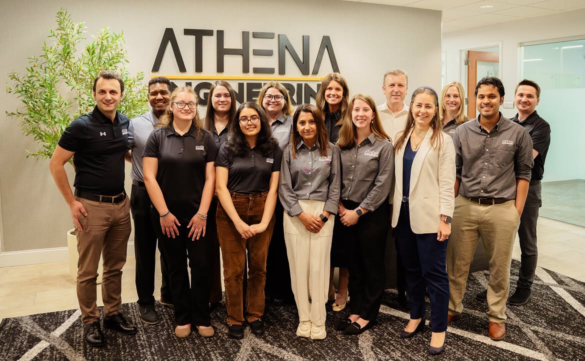 The Athena Engineering team photographed in front of the branded office signage